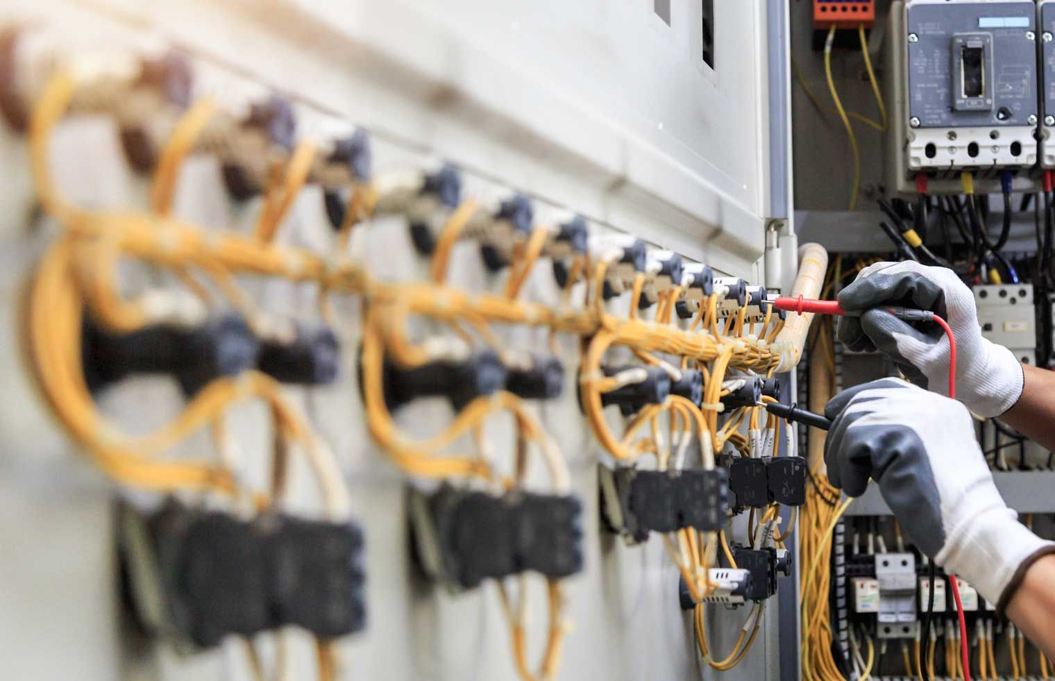 A man is working on an electrical box with wires hanging from it