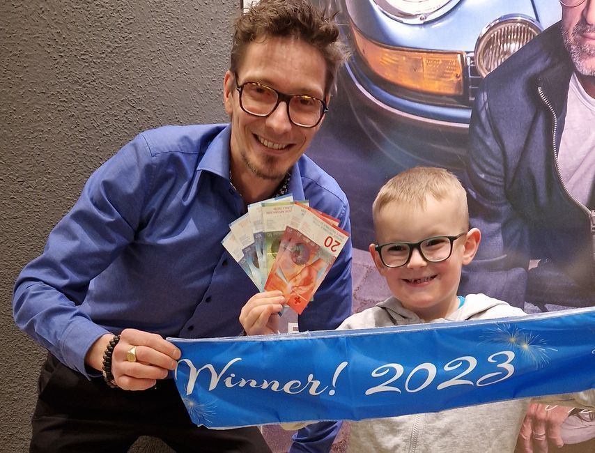 Ein Mann und ein Junge halten ein Schild mit der Aufschrift „Gewinner!“ in der Hand. 2023.
