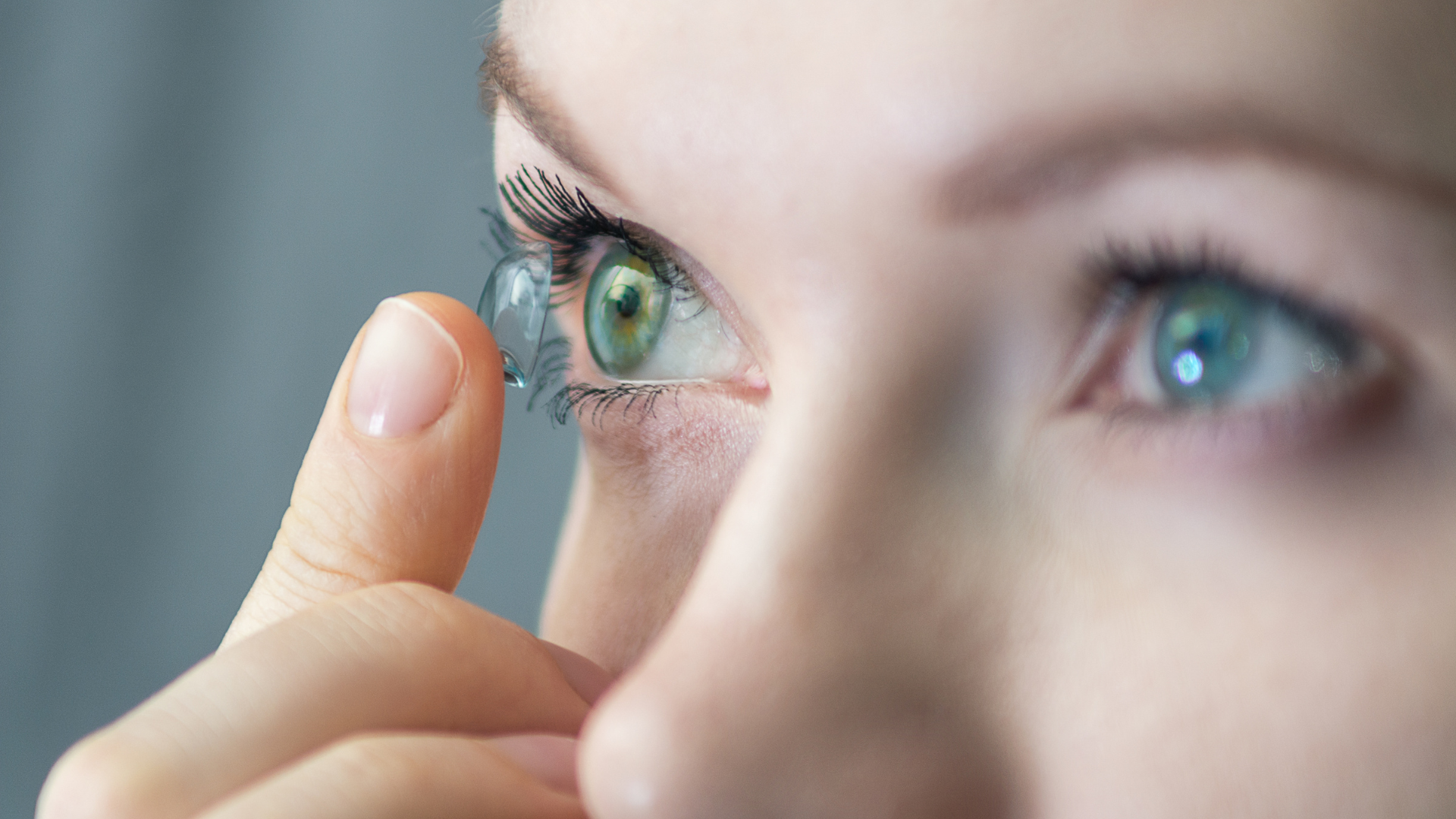 Eine Frau legt eine Kontaktlinse in ihr grünes Auge .
