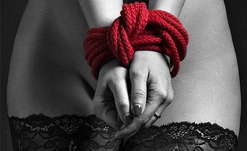 foto di donna con calze autoreggenti e mani legate con laccio rosso