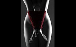 fotografia di donna nuda con mani legate da una corda rossa