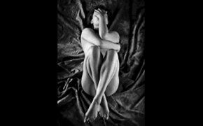 fotografia di donna nuda rannicchiata su coperta