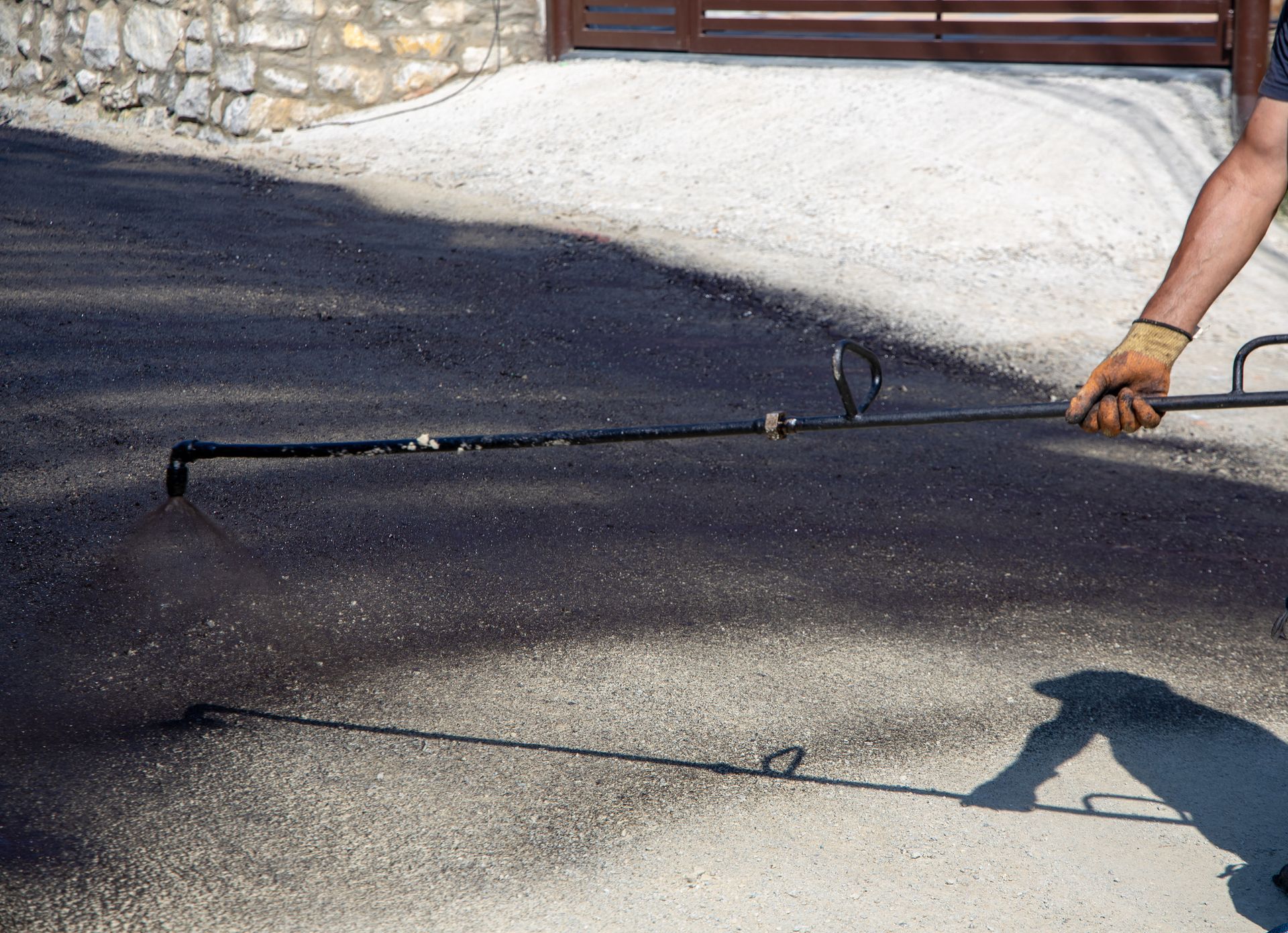 A man is spraying asphalt on a road with a sprayer.