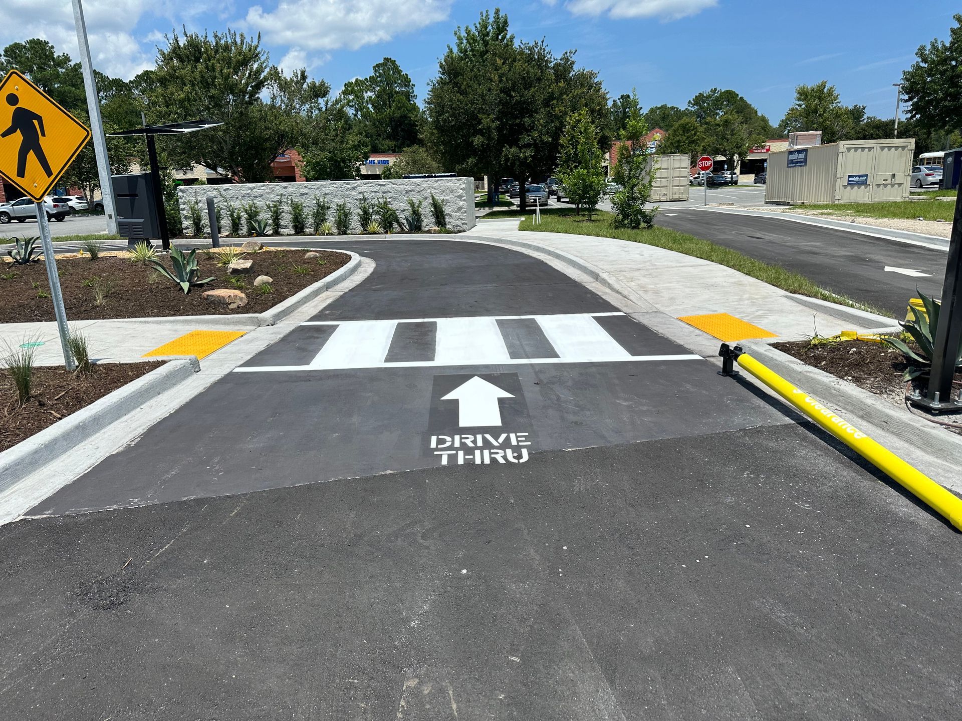 A man is kneeling down and painting a parking lot with a paint roller.