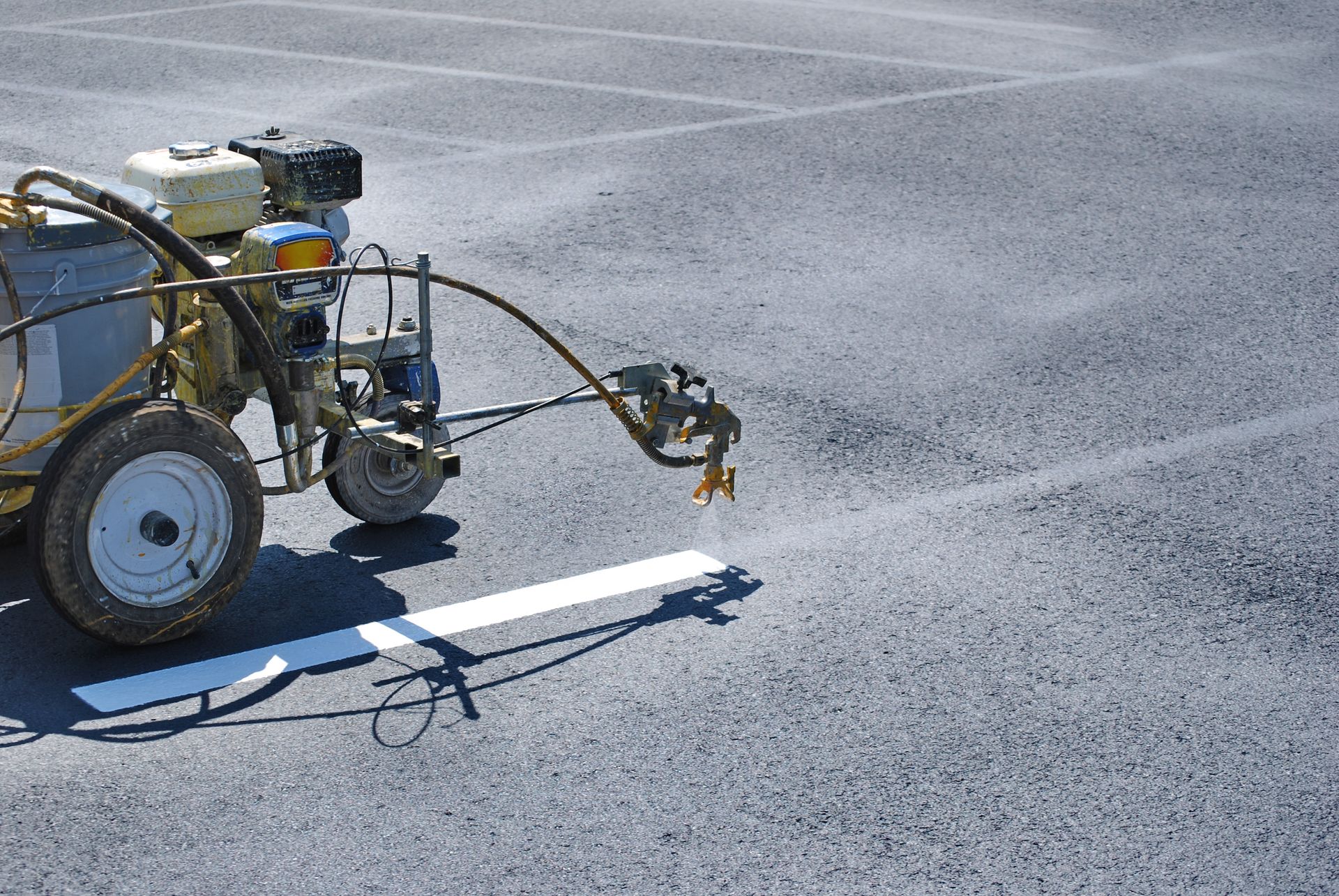 A machine is painting a white line on a parking lot.