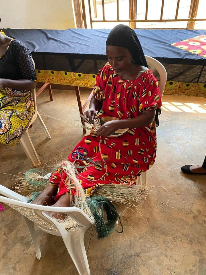 Woman in red dress weaving, sitting in a chair, indoor setting.