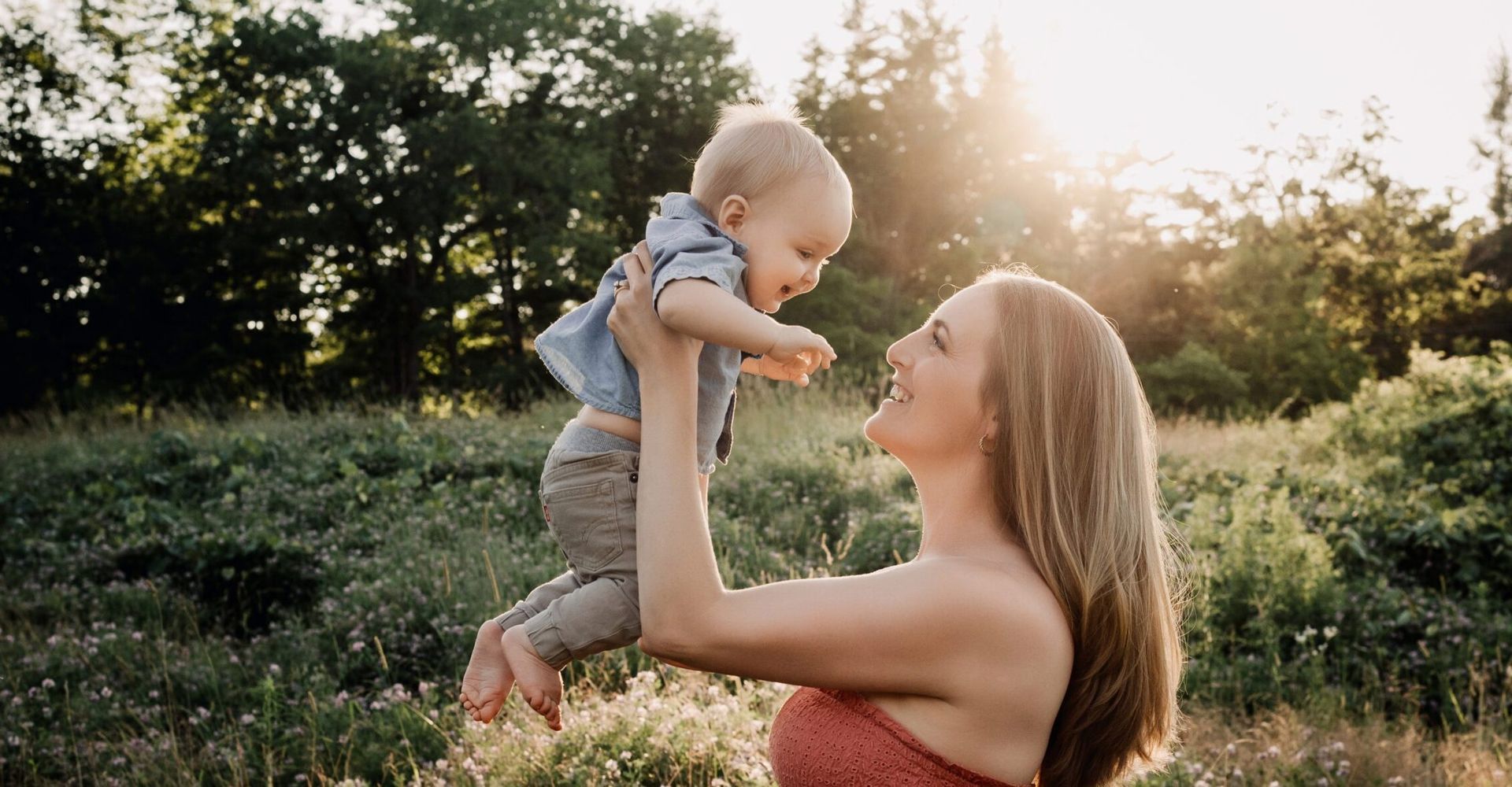 A woman is holding a baby in her arms in a field.