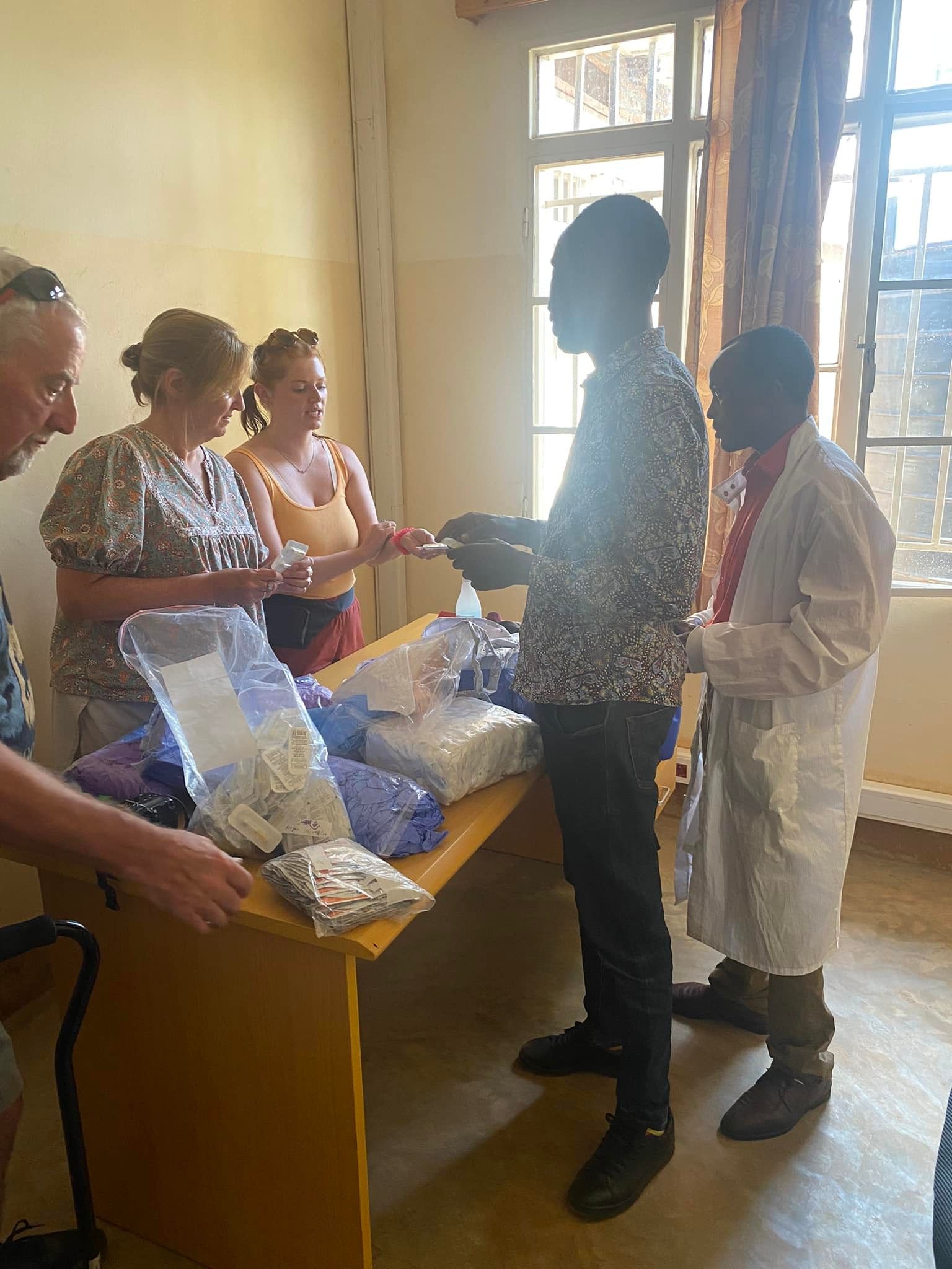 People in a room with a table of medical supplies, some handing out items.