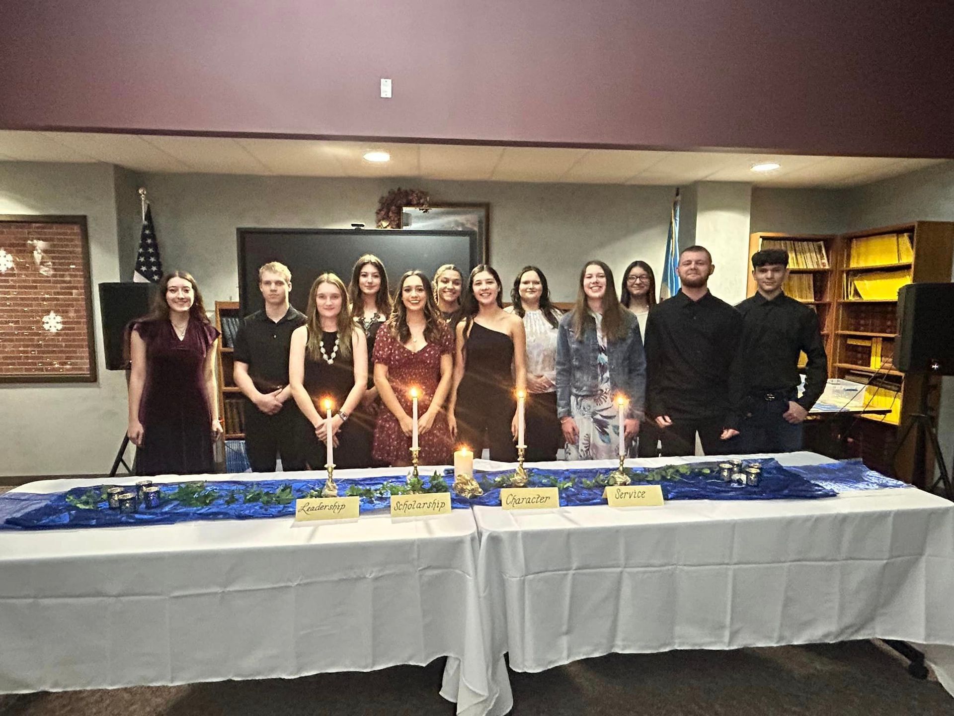 A group of people standing around a table with candles.