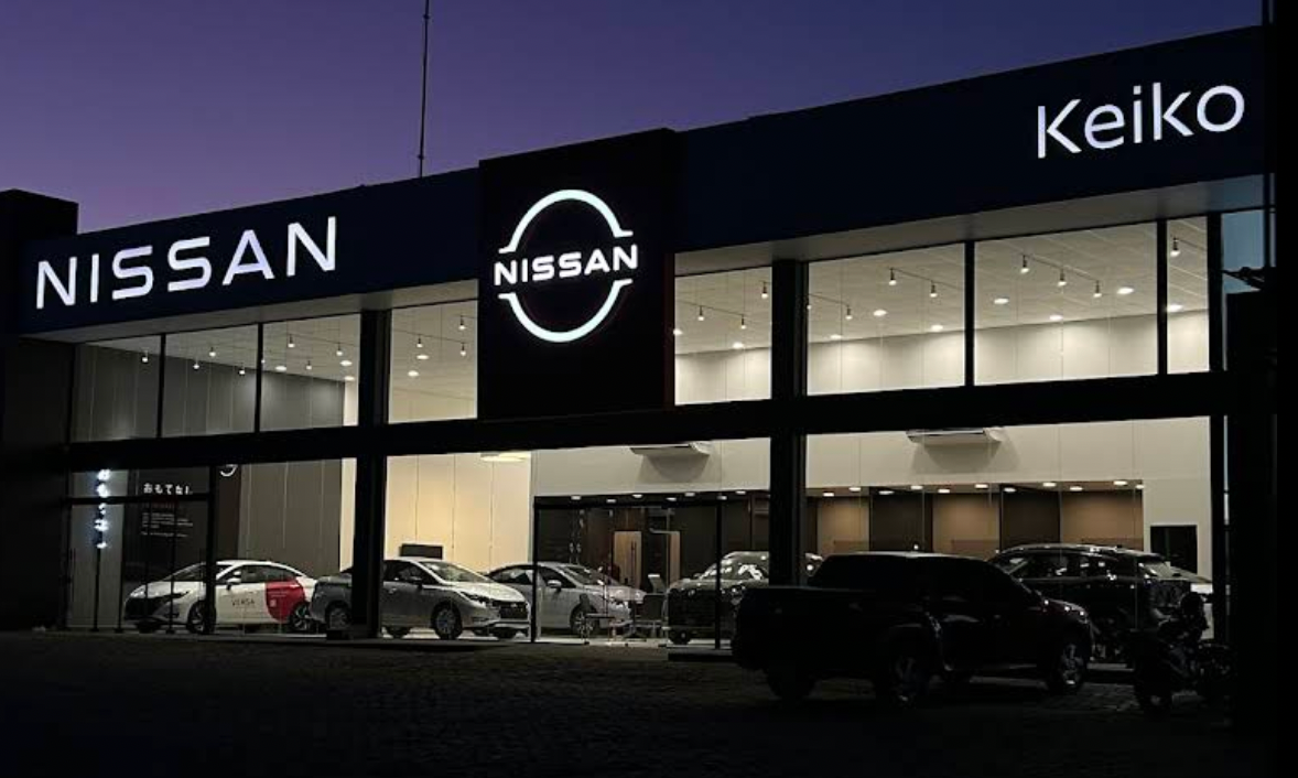 Fachada da concessionária Nissan com janelas de vidro e estacionamento em frente.