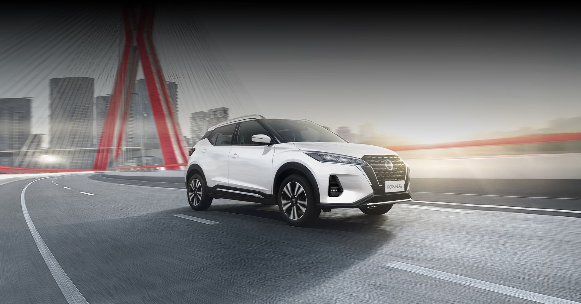 Um carro branco passa por uma rua da cidade ao lado de uma ponte.