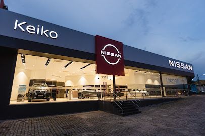 Fachada da concessionária Nissan ao entardecer, com showroom iluminado e placa 
