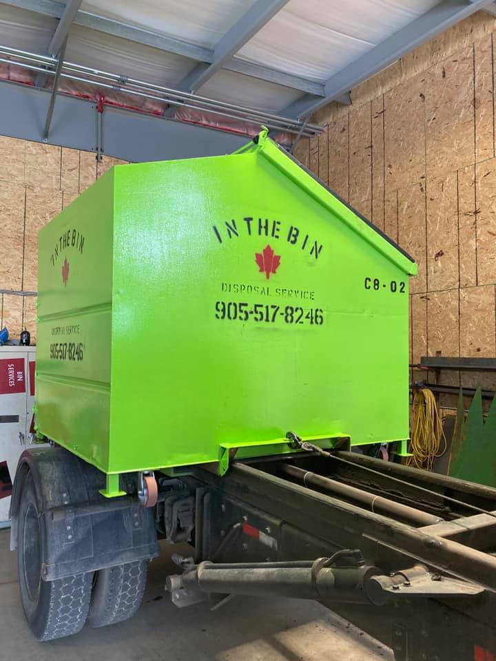 a green dumpster and a green portable toilet are parked next to each other .