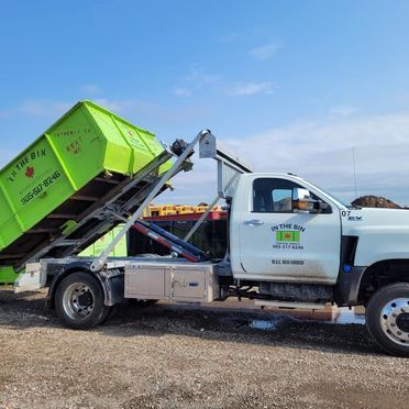 A truck carrying a green bin