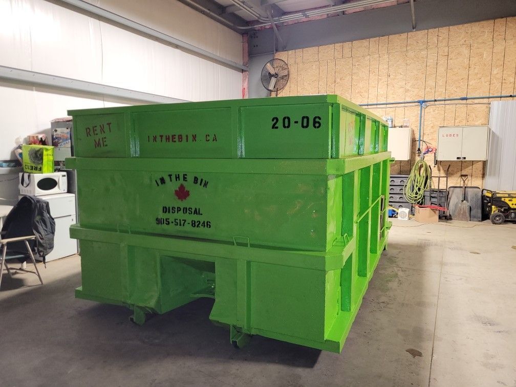 A large green dumpster is sitting in a garage.