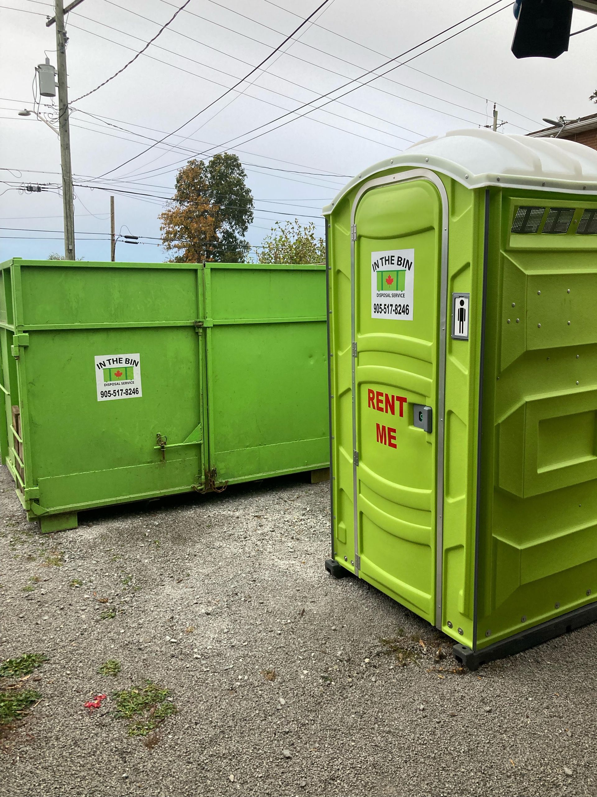 a green dumpster and a green portable toilet are parked next to each other .
