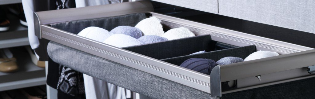 A drawer filled with balls of yarn in a closet.