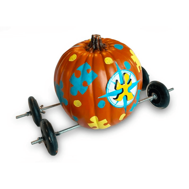 A pumpkin decorated with yellow and blue puzzle pieces, mounted on a metal axle with four black wheels.