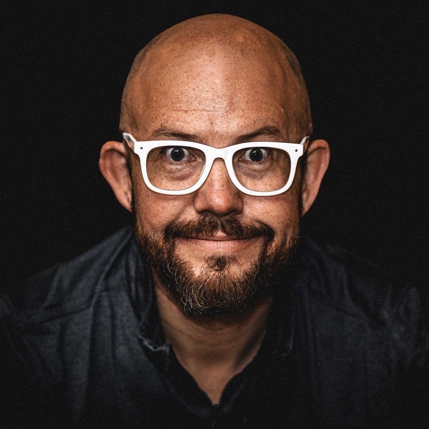 A man, John Benson, with a beard wearing white glasses