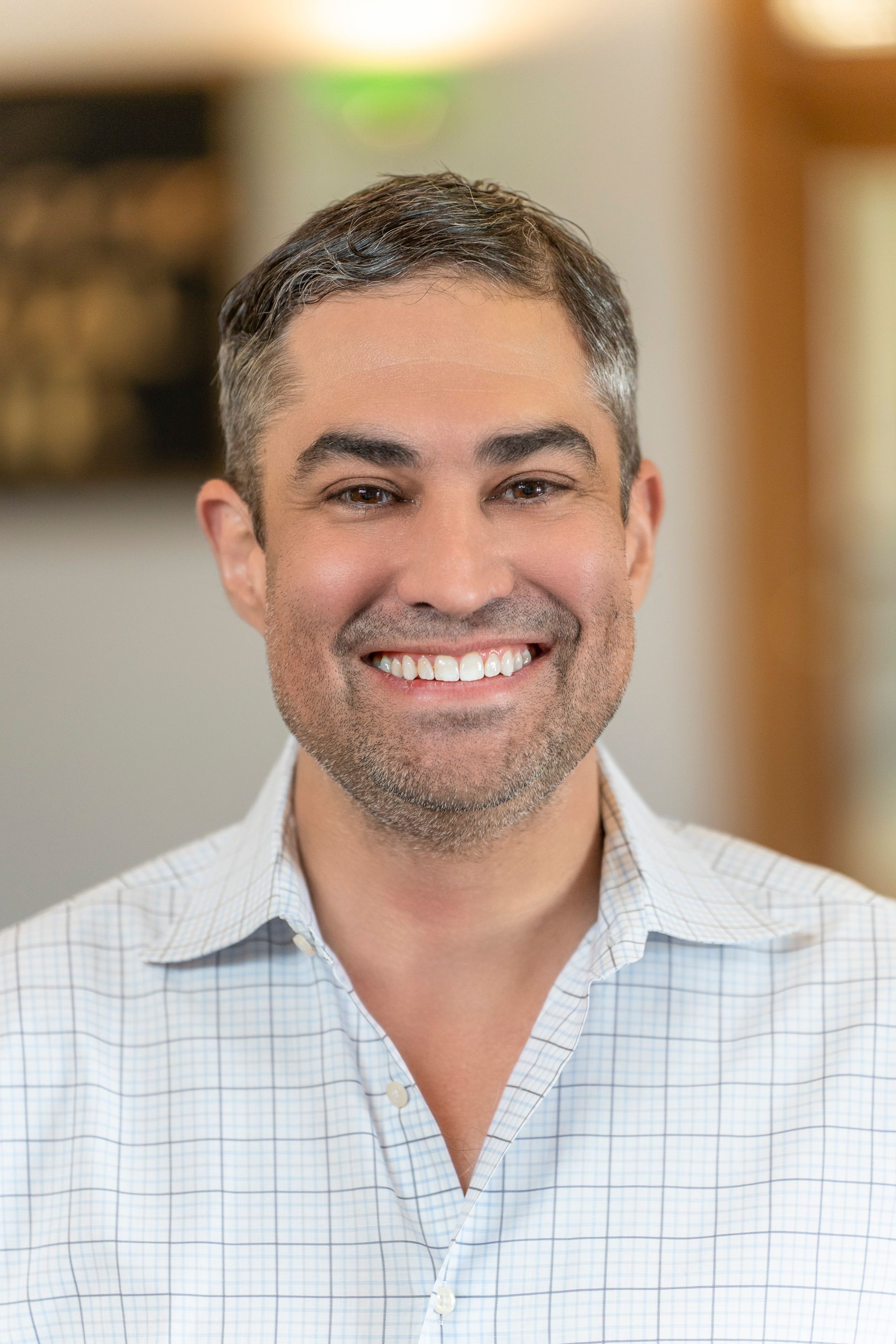 A man in a suit and white shirt is smiling for the camera.