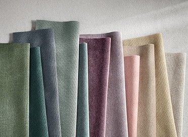 Stacked fabrics in colours ranging from green to dark pink to white. 