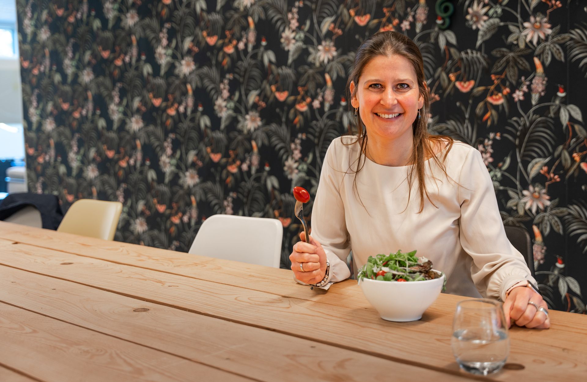 Een persoon glimlacht achter een heerlijke kom salade.