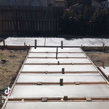 A concrete walkway is being built in a backyard.