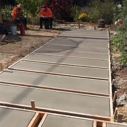 A concrete walkway is being built in a garden.