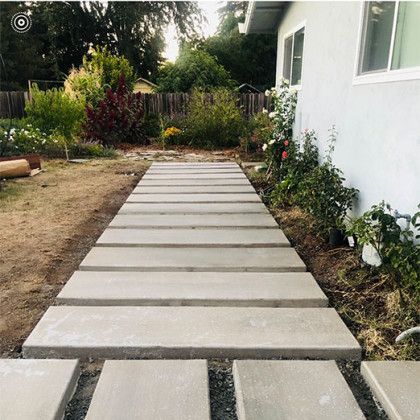 A concrete walkway leading to a house in a backyard.