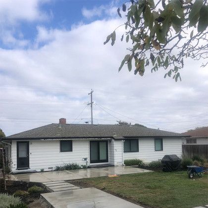 A white house with a gray roof is for sale.