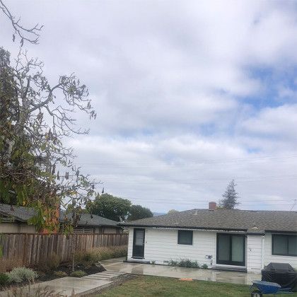 A white house with a gray roof is sitting on top of a lush green lawn.