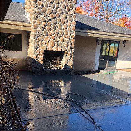 A house with a stone fireplace is being cleaned with a pressure washer.