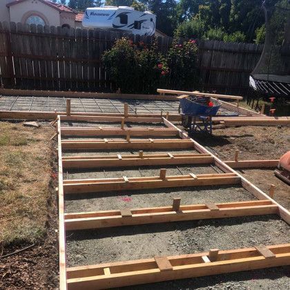 A concrete walkway is being built in a backyard.