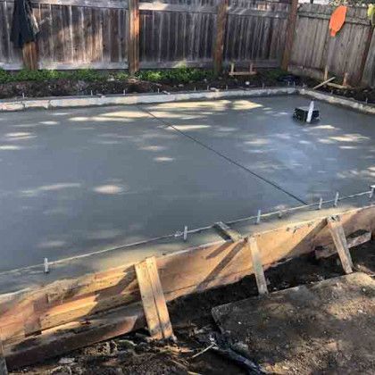 A concrete slab is being built in a backyard.