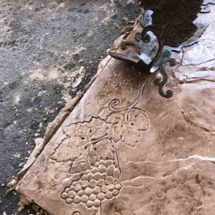A bunch of grapes are carved into a piece of concrete.
