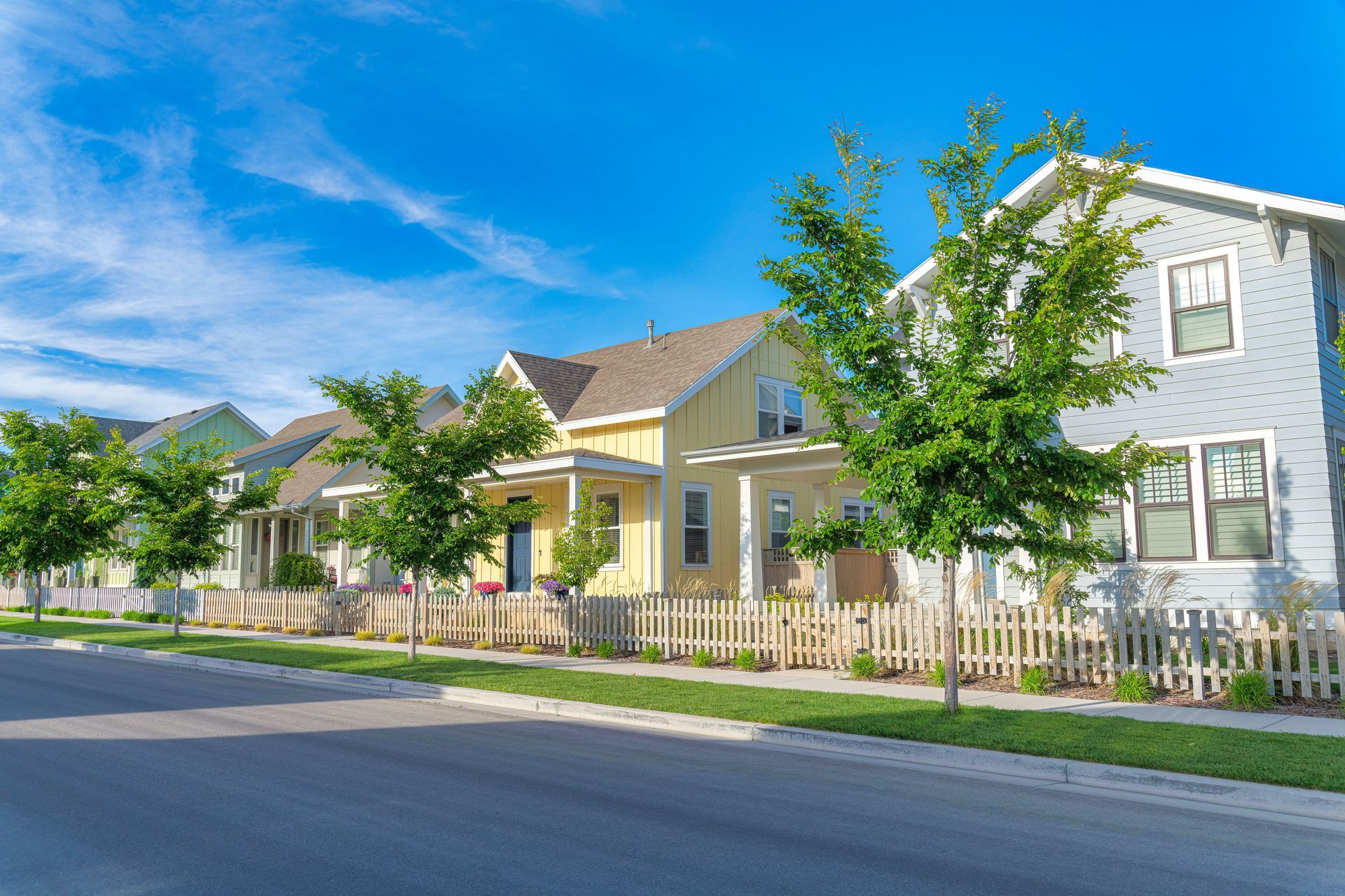 A row of houses with a white picket fence in a residential neighborhood.
