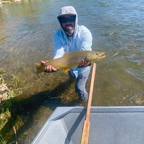 A man is holding a large fish in his hands while standing on a boat in the water.