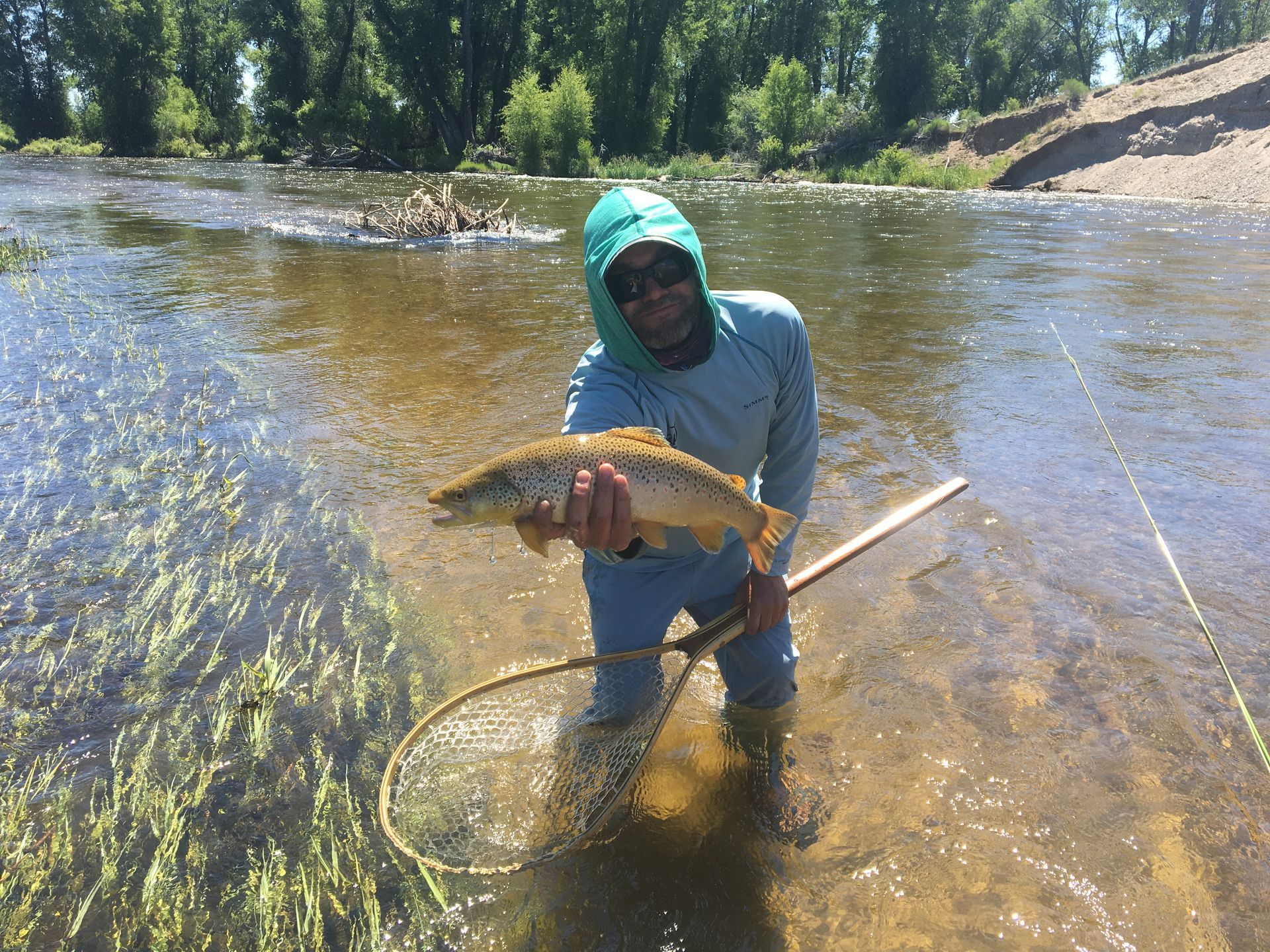 A man is kneeling in the water holding a fish.