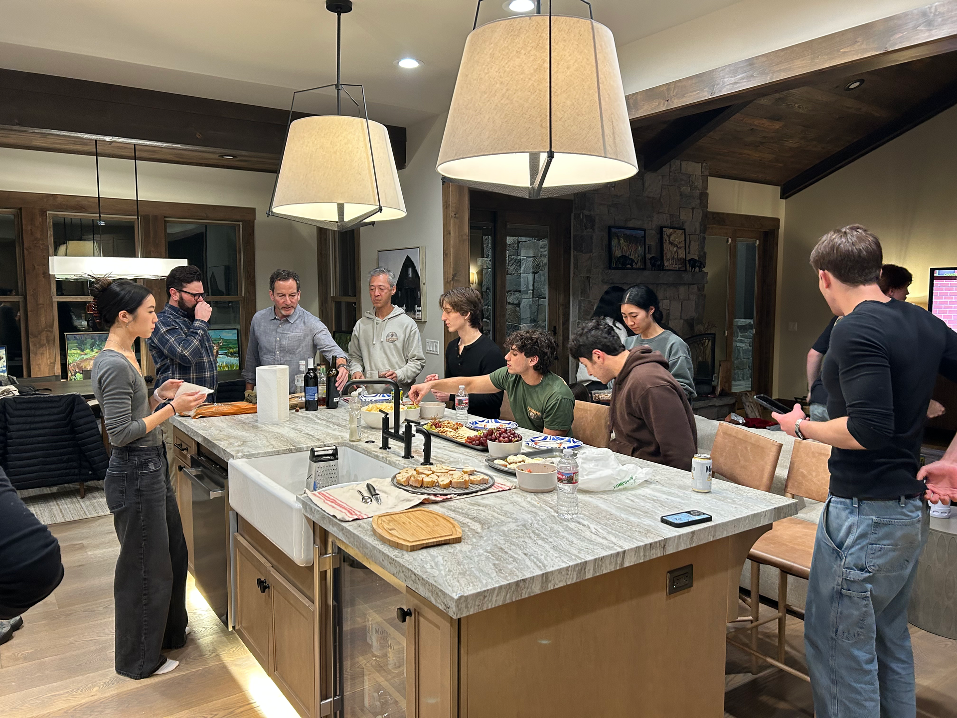 A group of people are standing around a large island in a kitchen.