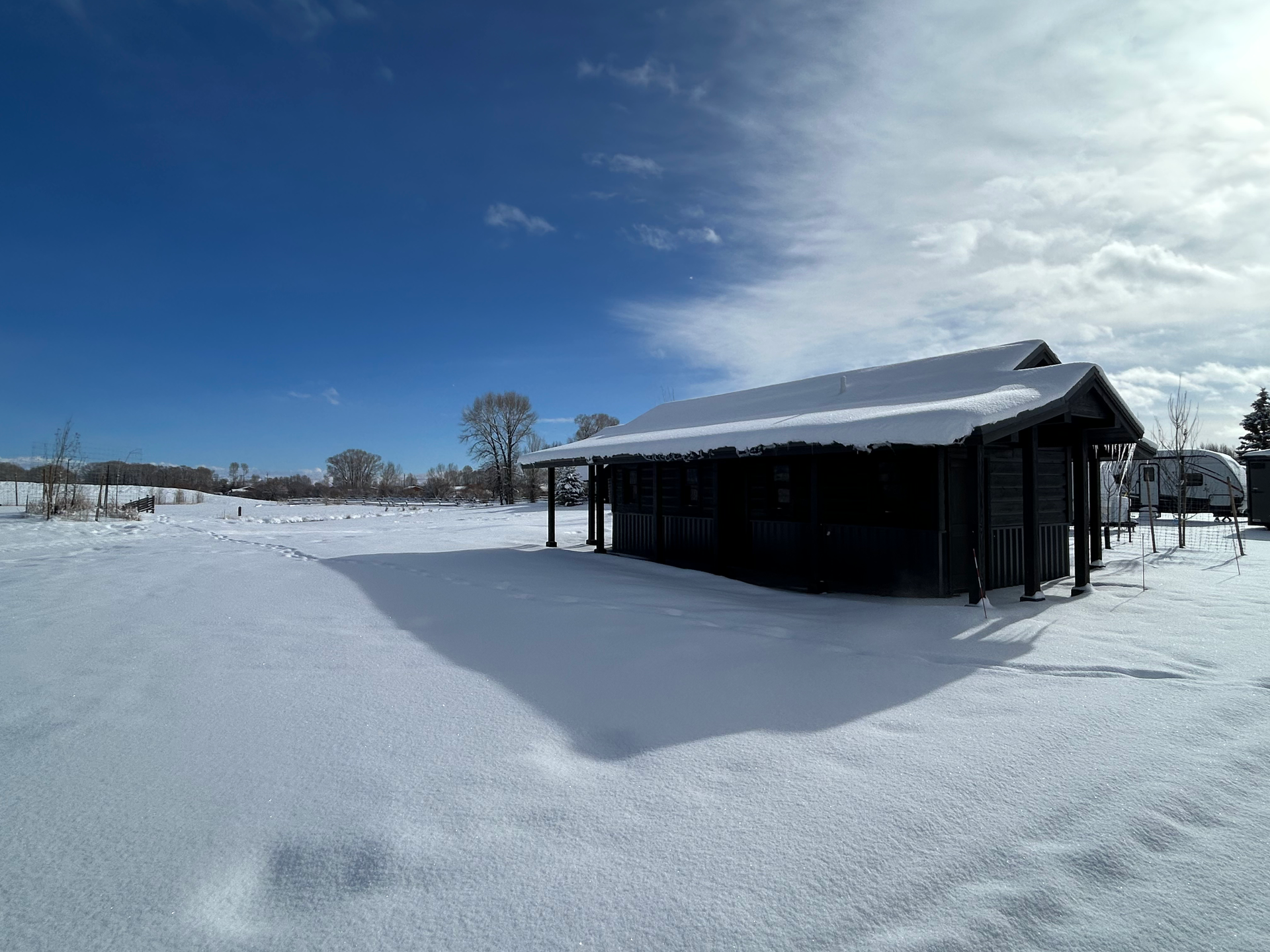 A small house is sitting in the middle of a snow covered field.