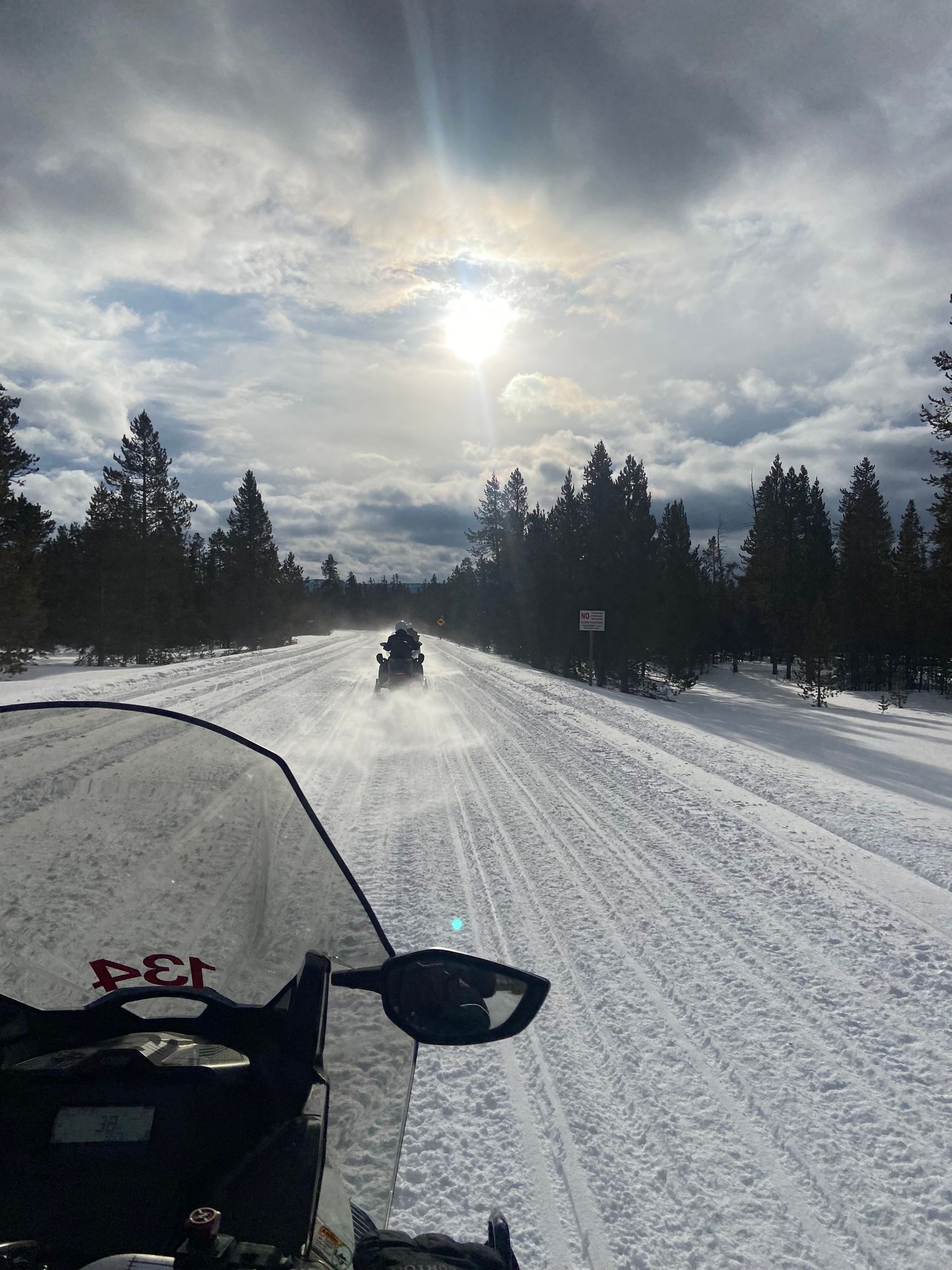 A snowmobile is driving down a snow covered road.