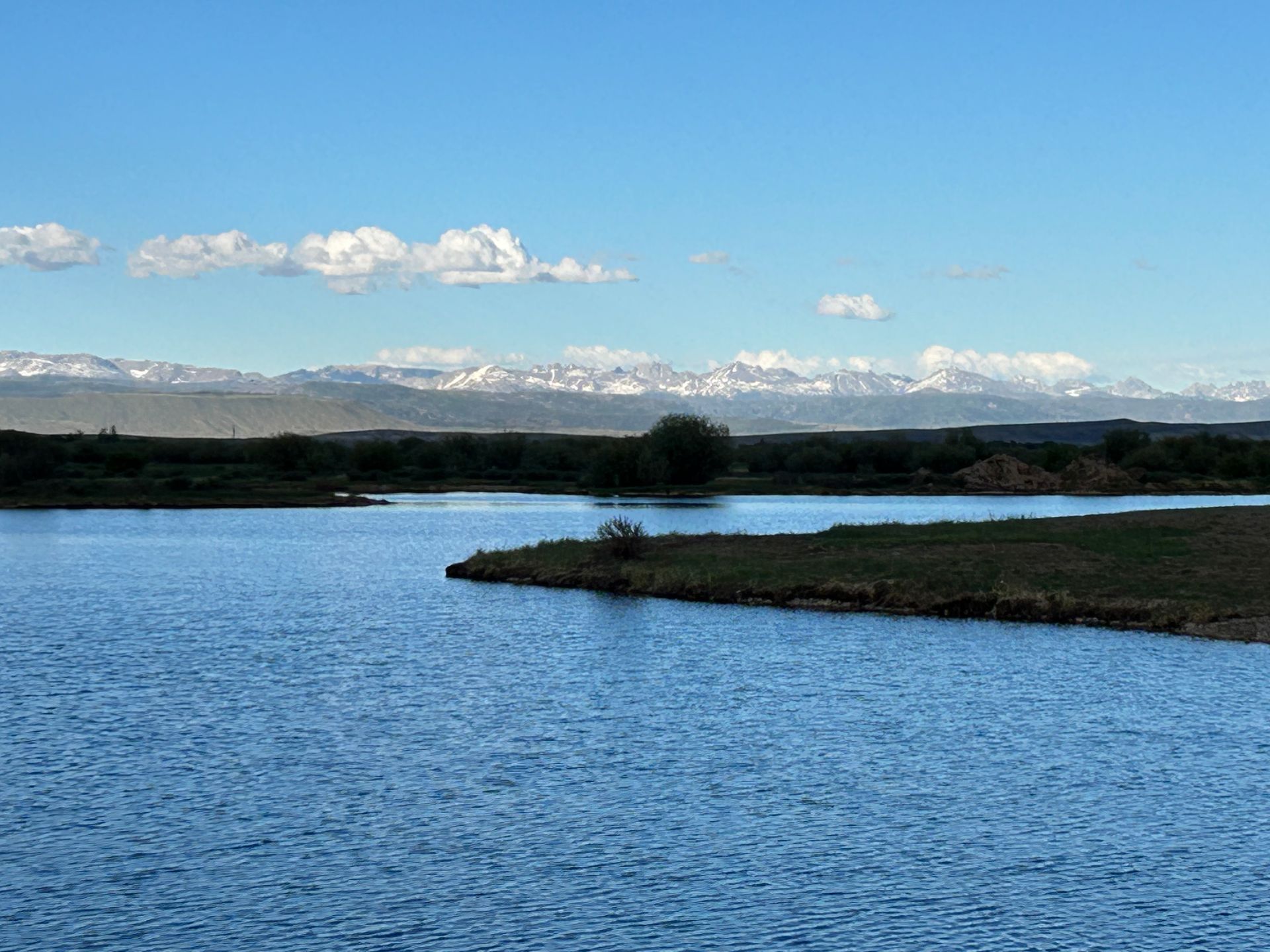 A large body of water with mountains in the background and a small island in the middle.