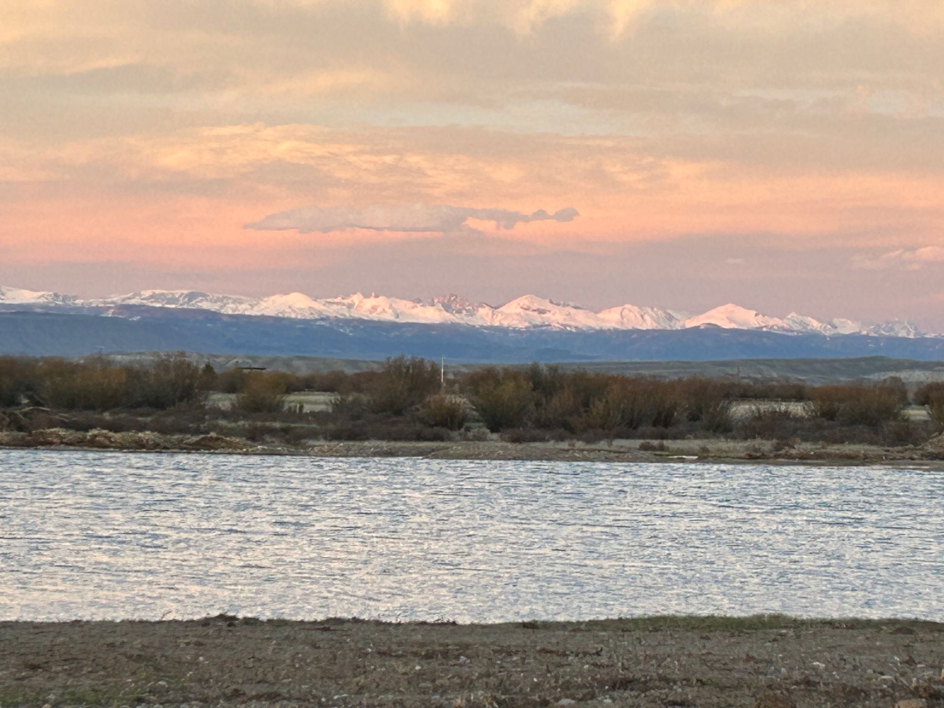 A large body of water with mountains in the background at sunset.