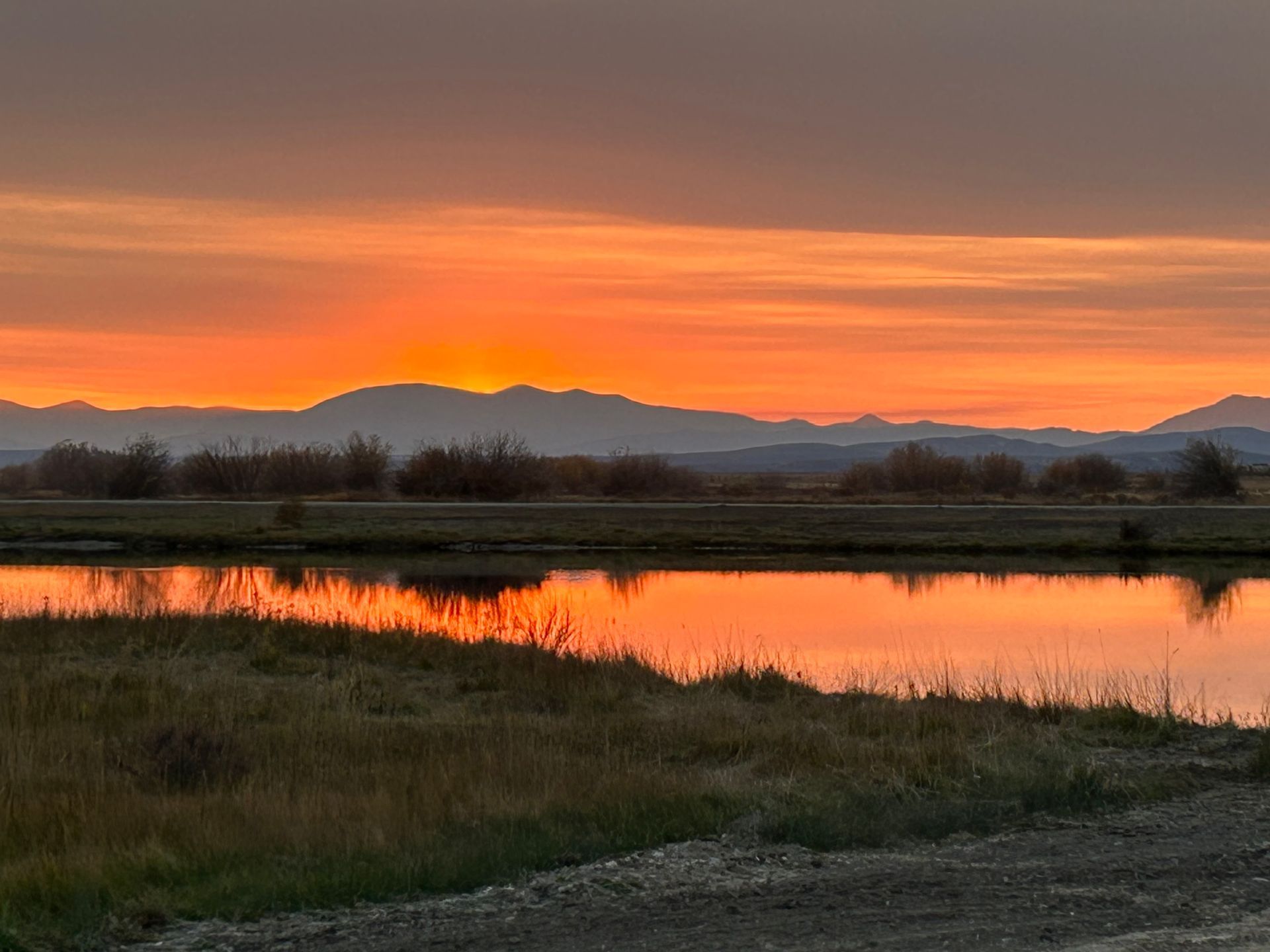 A sunset over a lake with mountains in the background