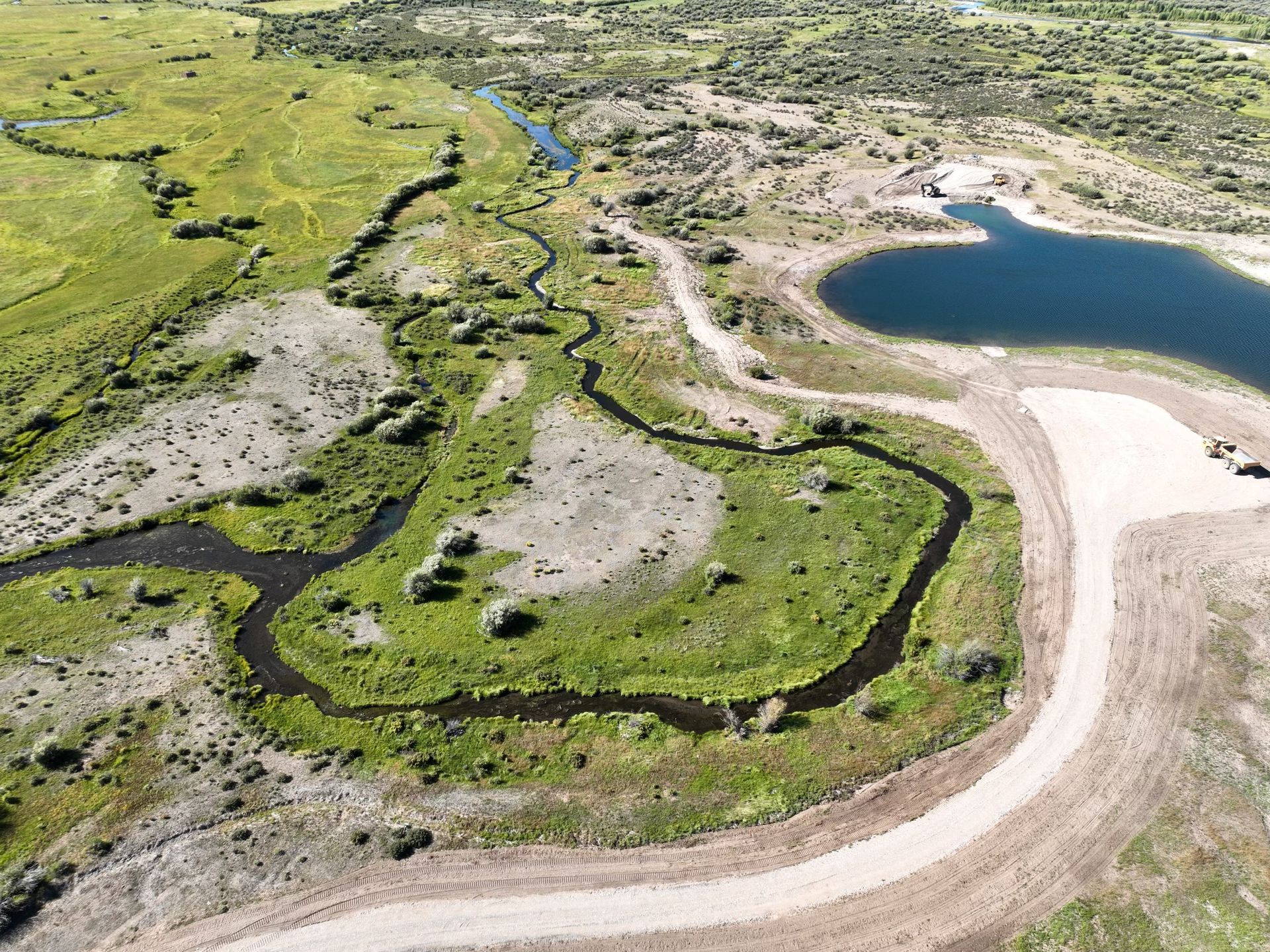 An aerial view of a swamp with a lake and a dirt road.