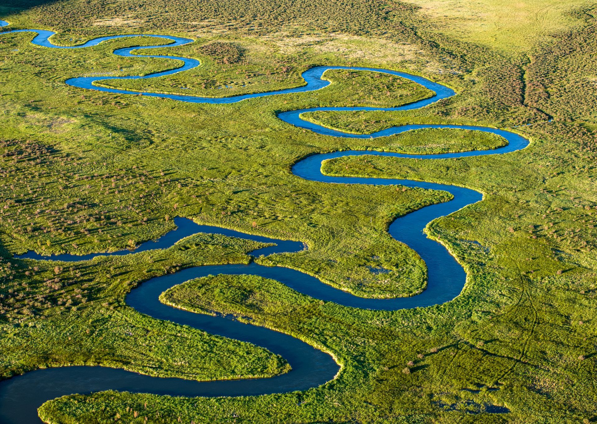 An aerial view of a river winding through a lush green field