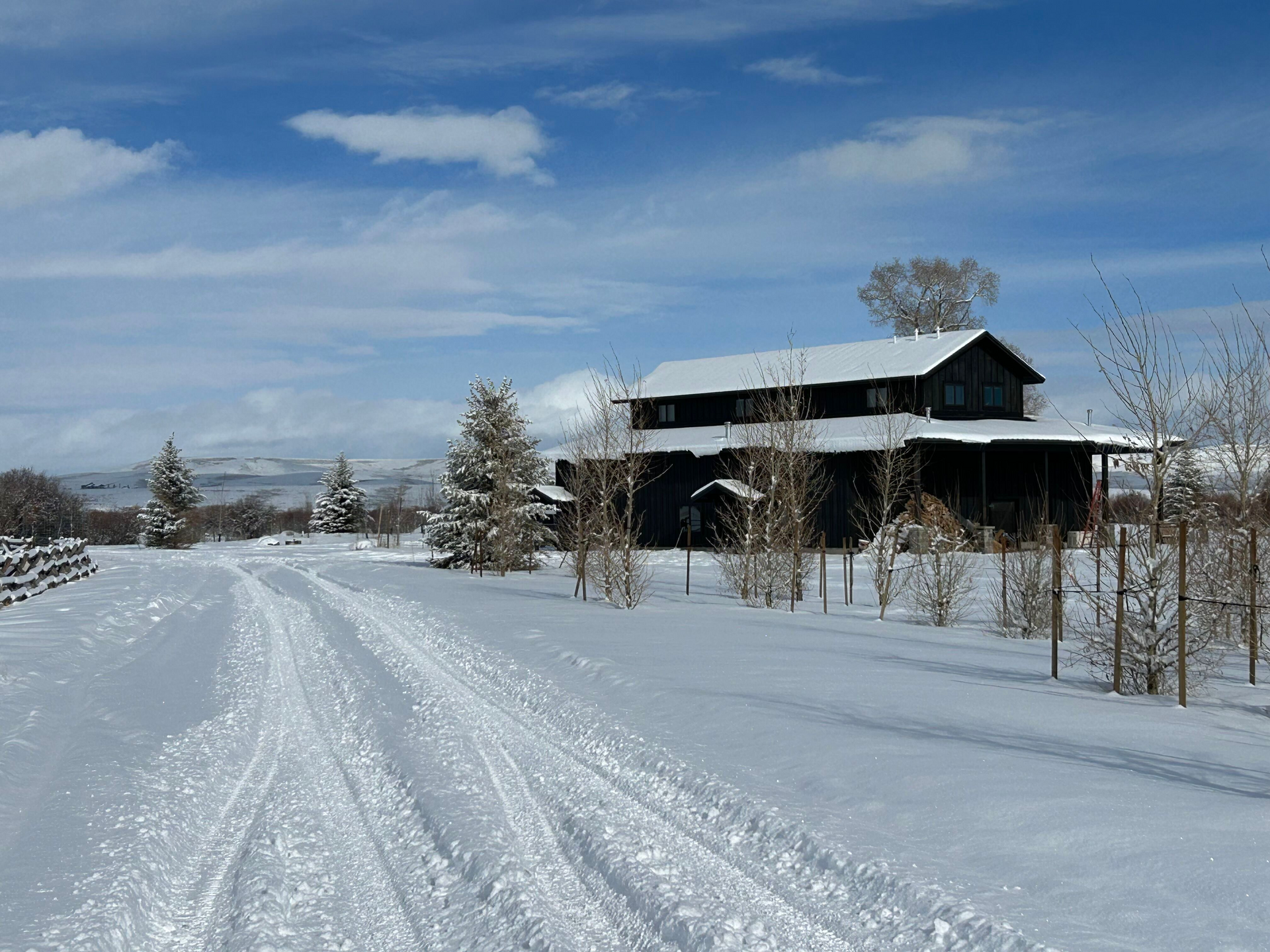 A snowy landscape with a house in the background