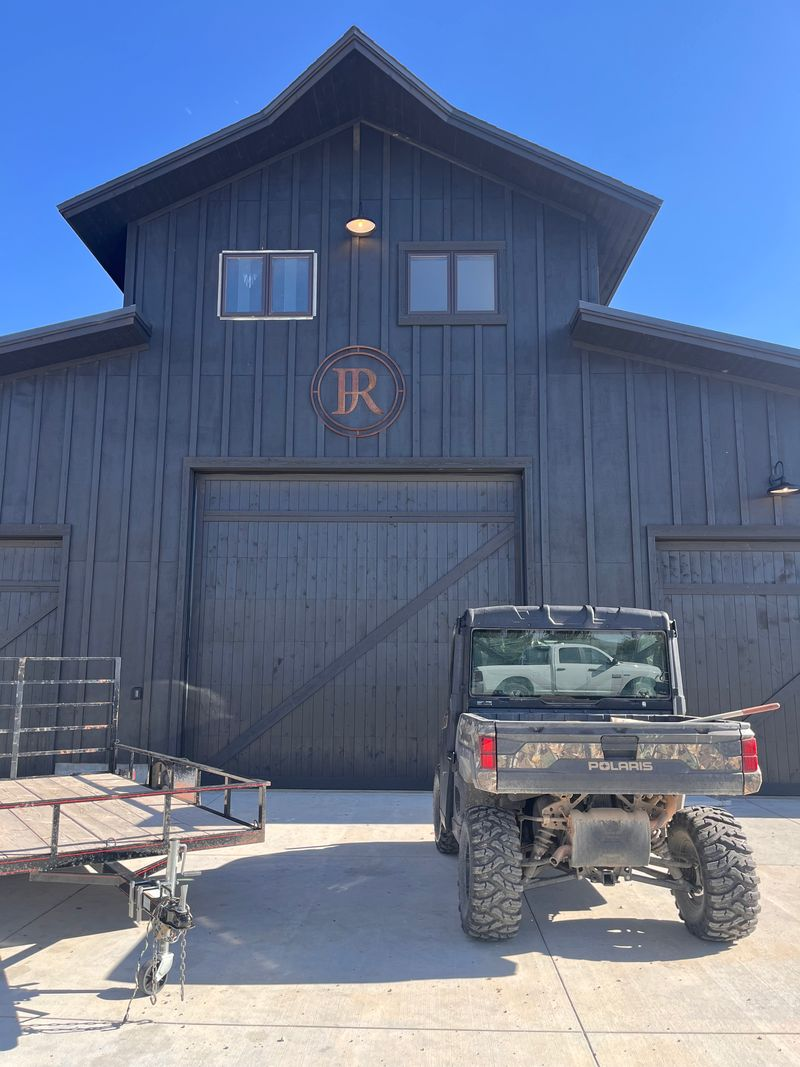 A jeep is parked in front of a large barn.