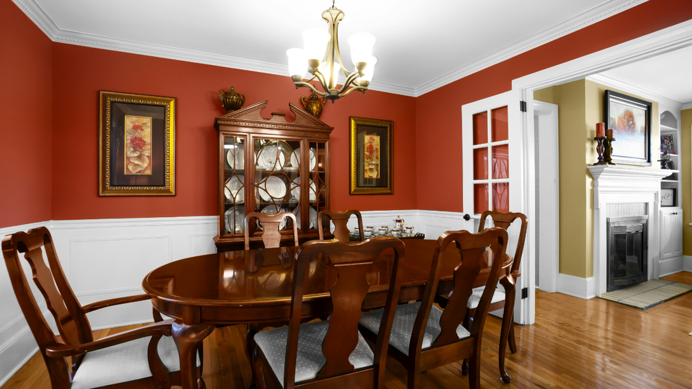 Formal dining room with red walls, white trim, wood table and chairs, and a china cabinet.