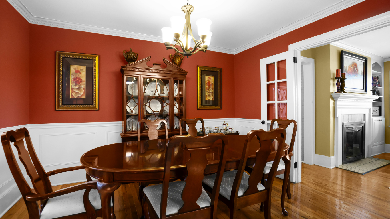 Formal dining room with red walls, white trim, wood table and chairs, and a china cabinet.